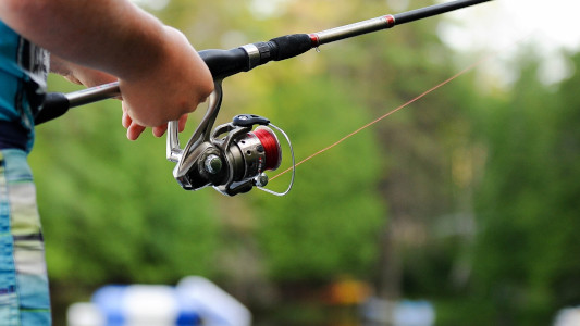 fishing rod being held by pair of hands
