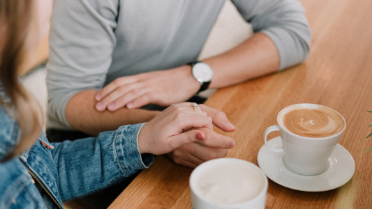 two people holding hands next to a cup of coffee