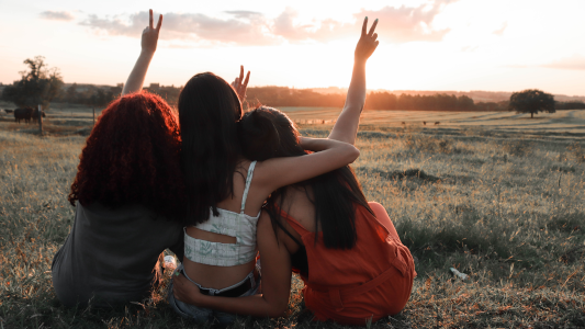 Three girls sitting and hugging in the countryside