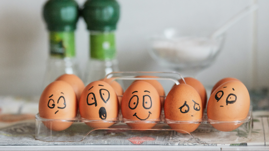 A tray of eggs with facial expressions drawn on them with black marker pen