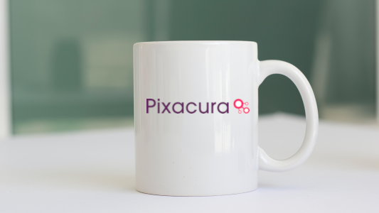A white coffee with the Pixacura name and logo printed on it
