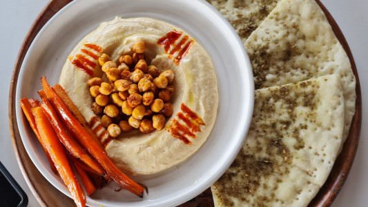 A plate with chillies and hummus and chickpeas