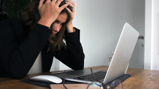 woman stressed at laptop with her head in her hands