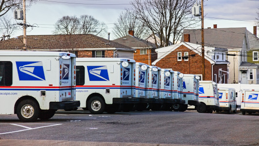Row of USA postal trucks parked in depot